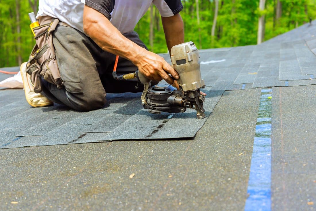 Roofer nailing down shingles